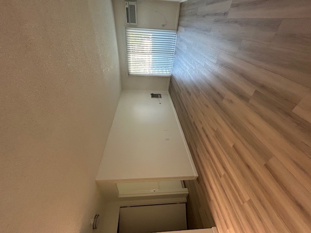 A room with a wooden floor and a white wall.